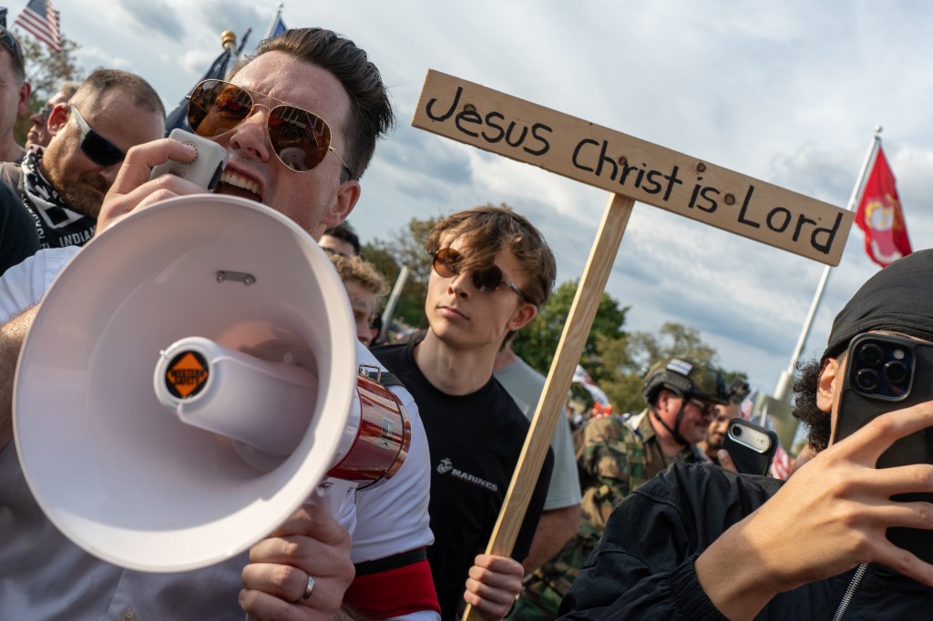 A man (Trevor Raien) wearing a swastika armband leads an anti-Jake Lang crowd during protests both for and against Jake Lang at the Henry Ford Centennial Library on 8.18.26 in Dearborn, MI